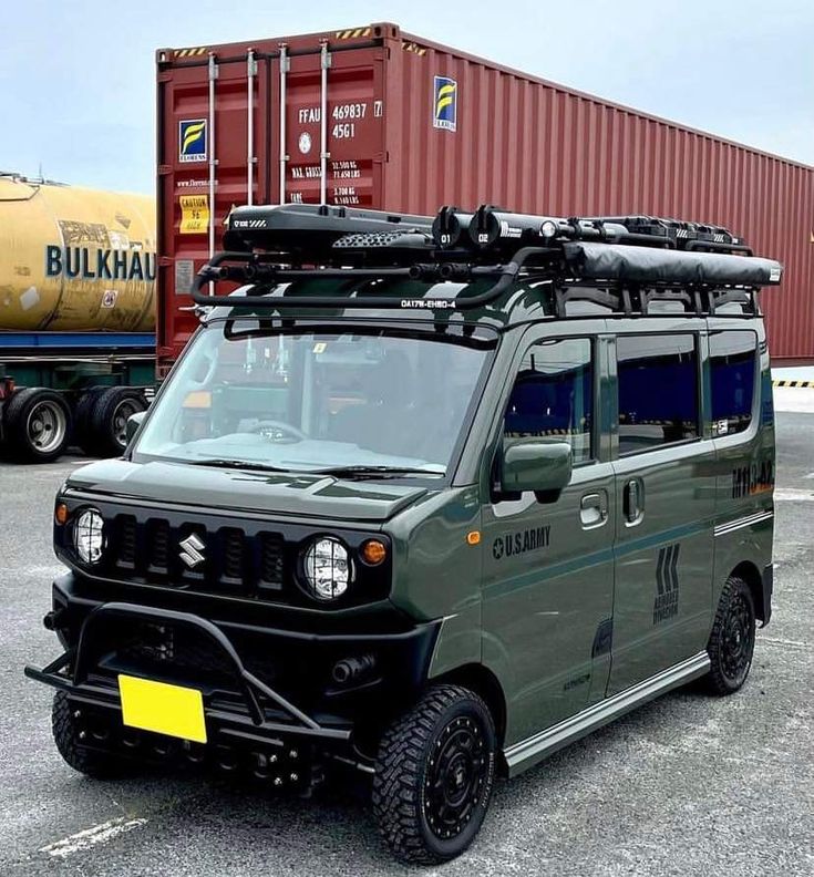 an army green vehicle parked in front of a cargo container