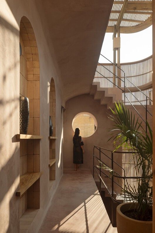 a woman is standing in the middle of a long hallway between two walls with arched windows