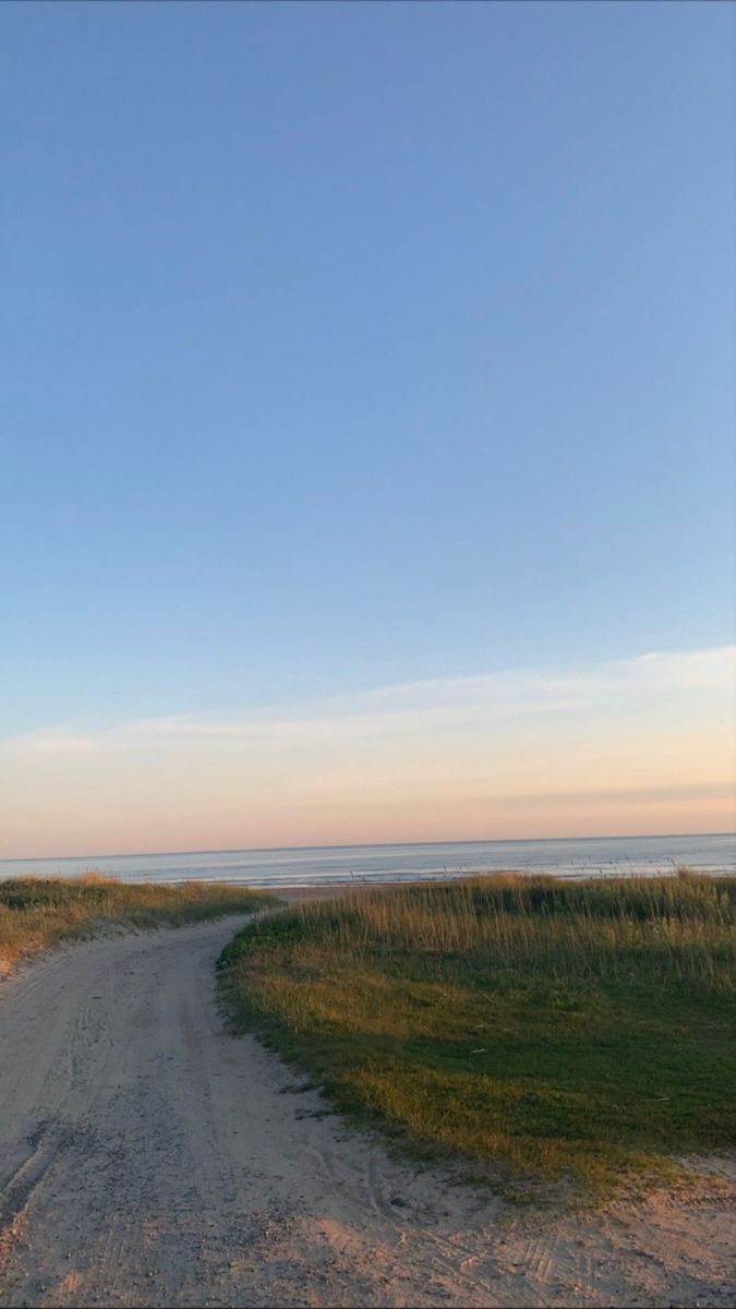 an empty dirt road next to the ocean