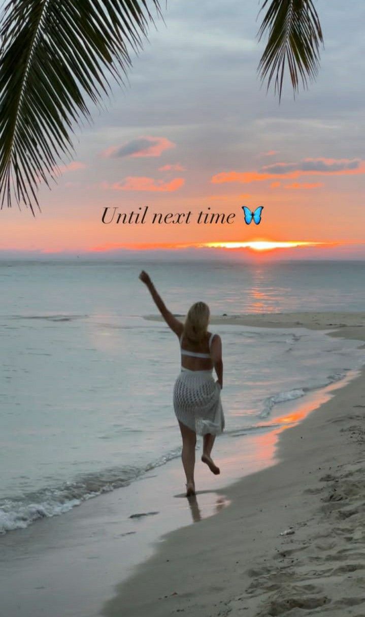 a woman is running on the beach with her arms in the air as the sun sets