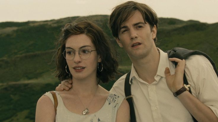 a man and woman standing next to each other in front of a green mountain range