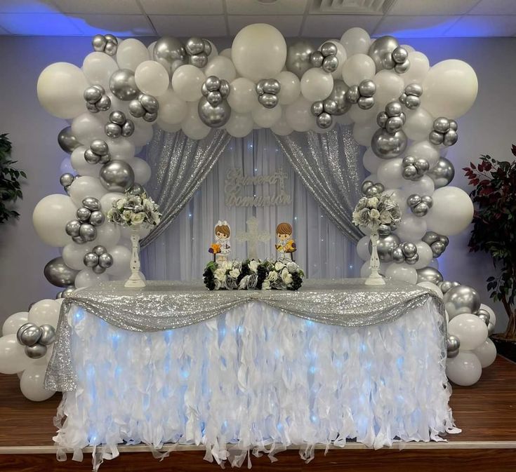 a table topped with white and silver balloons