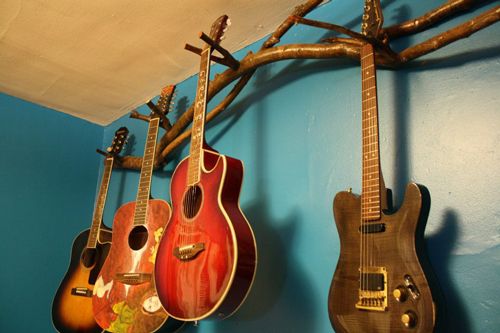 three guitars are hanging on the wall next to each other in a room with blue walls