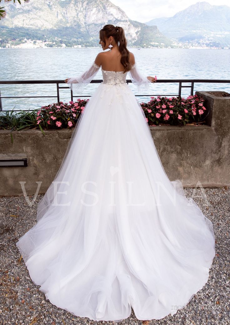 a woman in a wedding dress looking out over the water