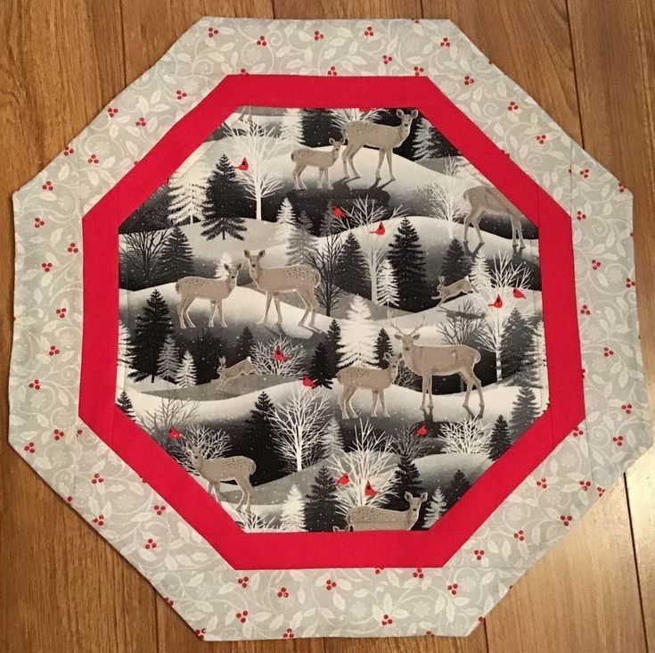 a red and white plate with deer in the woods on it's side, sitting on a wooden floor