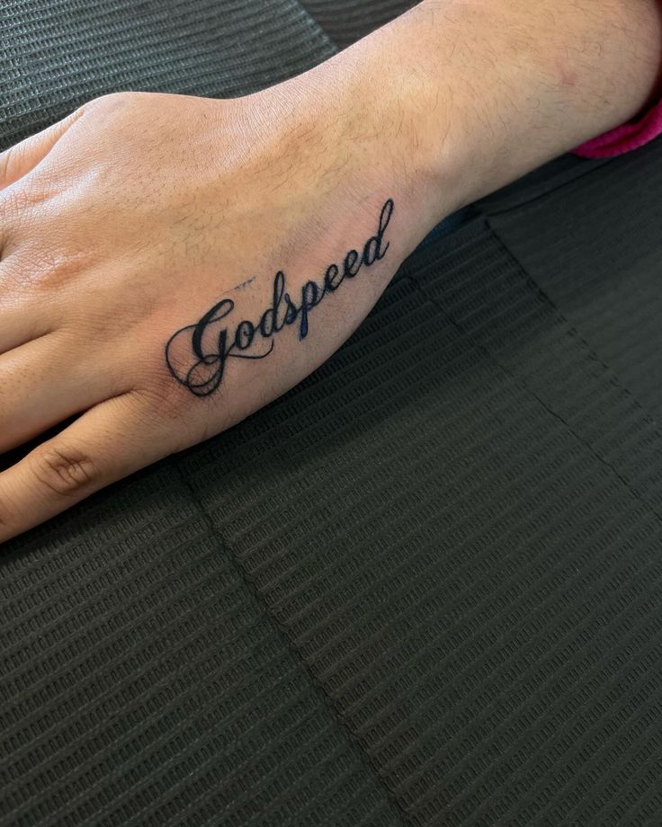 a person's hand with a small tattoo on it that says god speed in cursive writing