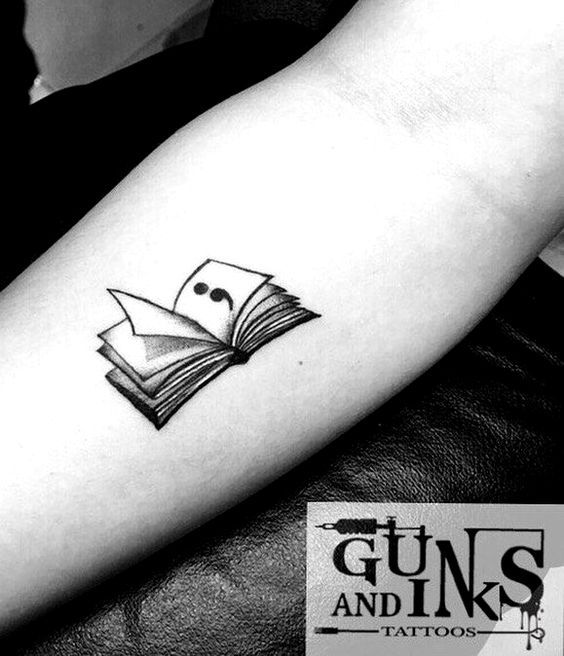 a black and white photo of a book tattoo on the arm