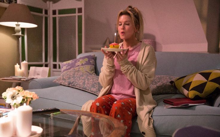 a woman sitting on top of a couch holding a plate with food in her hands