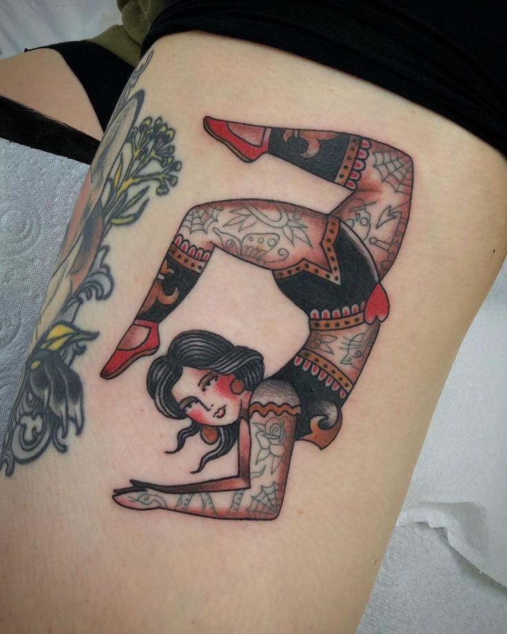 a woman with tattoos on her leg doing a handstand in the shape of a letter