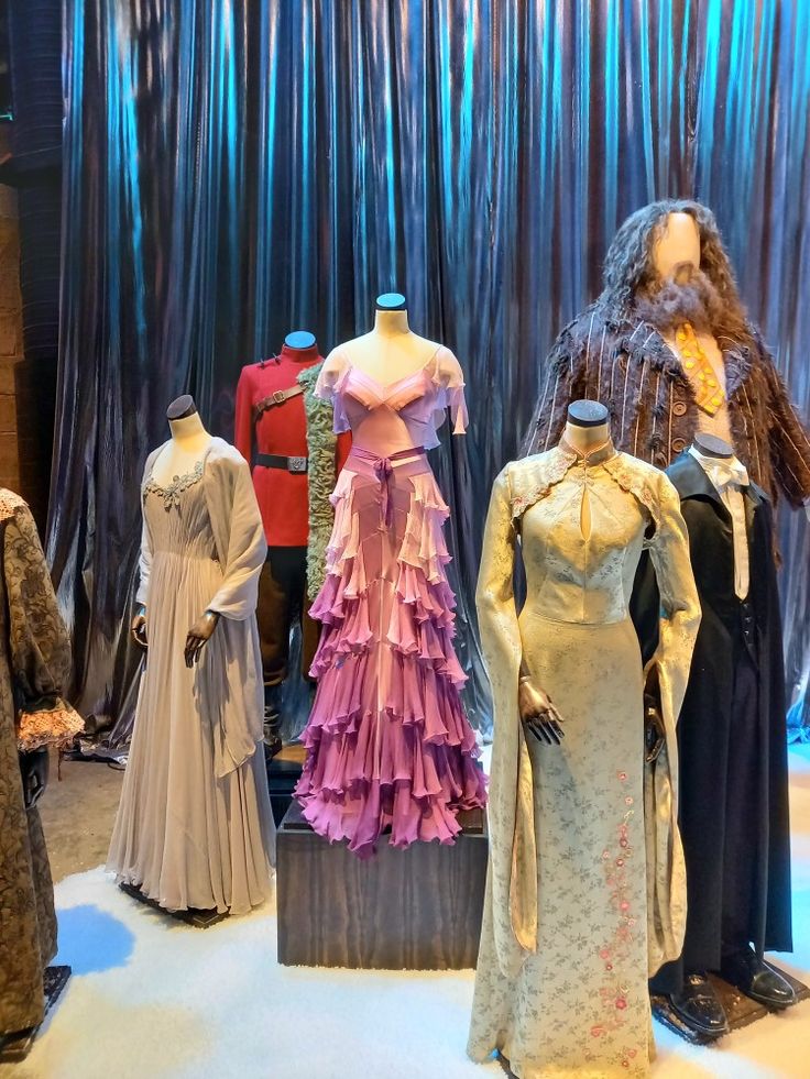 several mannequins and dresses on display in front of a curtain