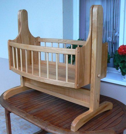 a wooden baby crib sitting on top of a table next to a flower pot