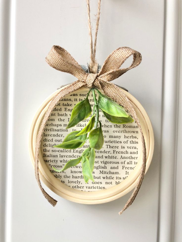 an ornament hanging on a door with a book page in the background and some green leaves tied to it