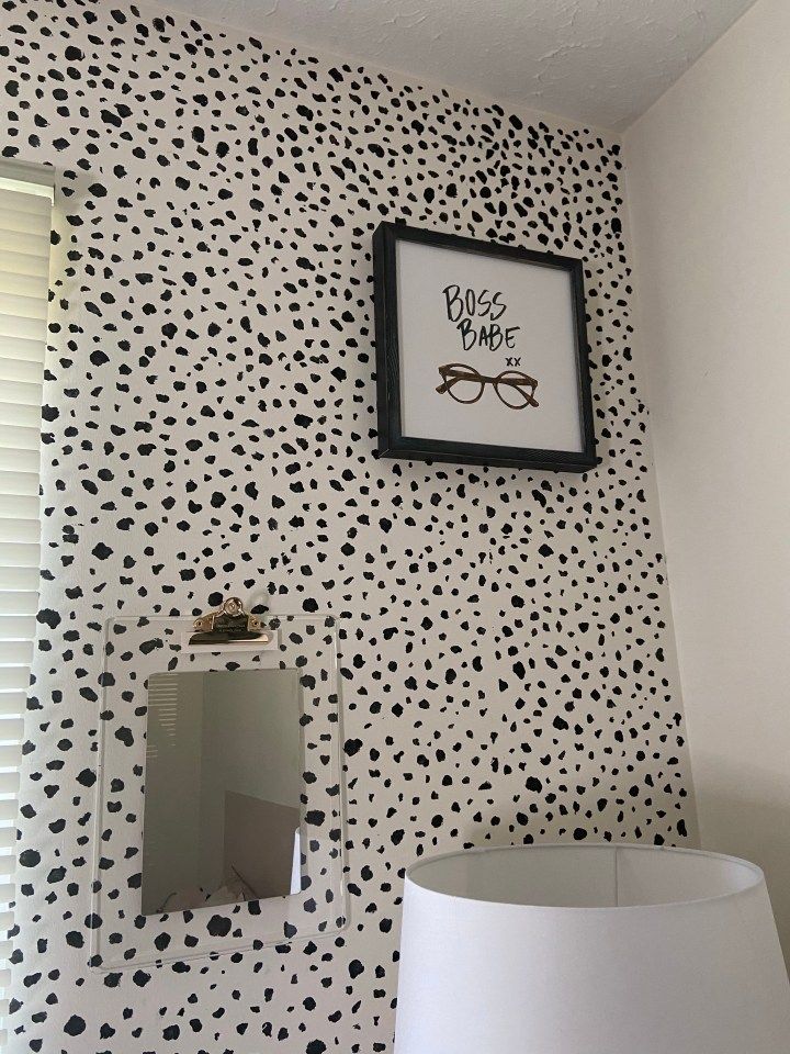 a white lamp sitting next to a wall with black and white spots on it's walls