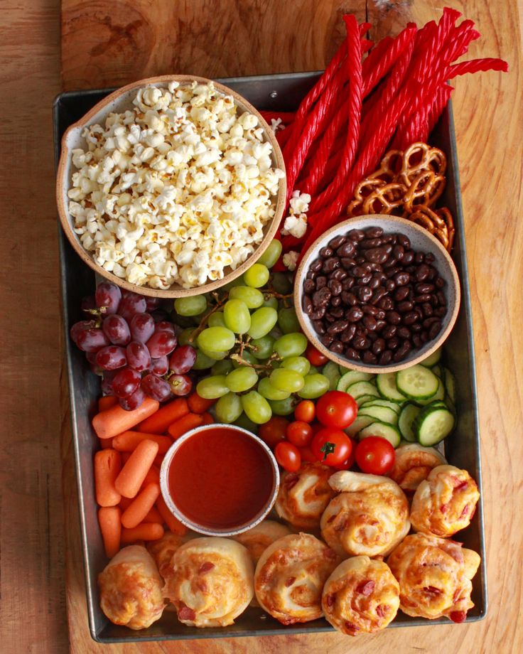 a tray filled with grapes, carrots, crackers and other foods next to some dipping sauce