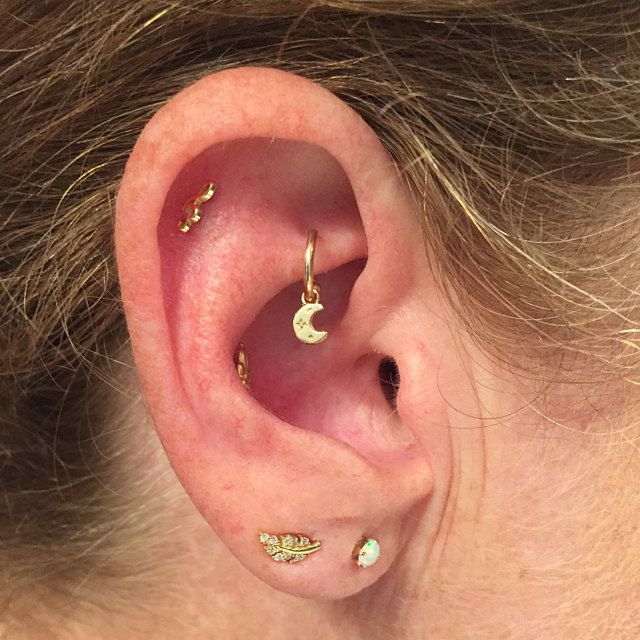 a woman with gold ear piercings on her left ear and the moon behind her ear