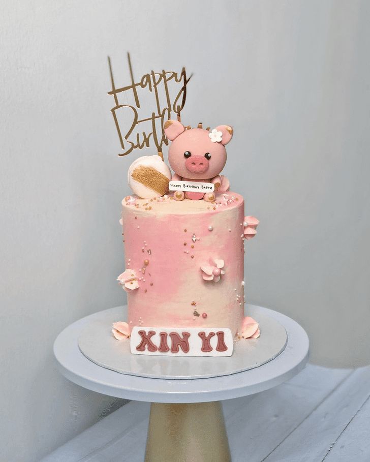 a pink birthday cake with a pig on top