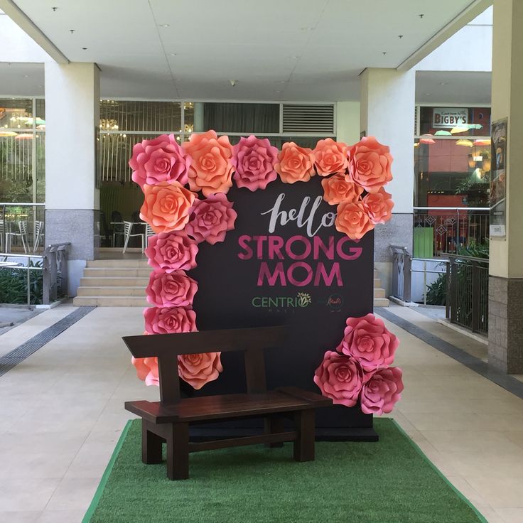 there is a sign that says hello strong mom with flowers on it and a bench in front