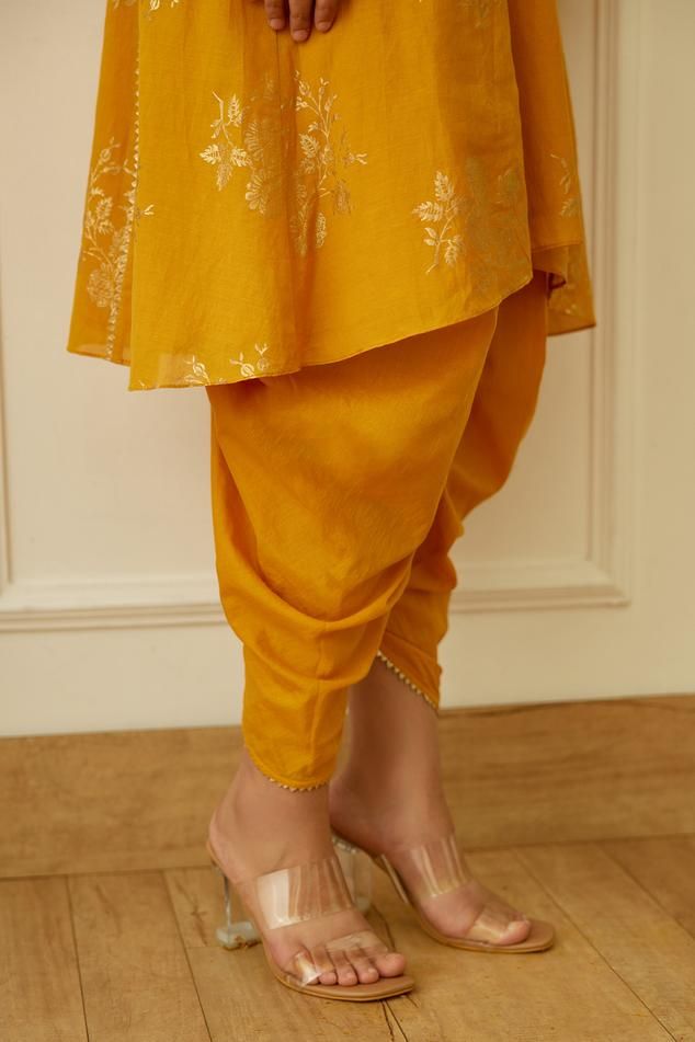 Ochre kurta with gold foil floral print and gota detail. Paired with tulip dhoti pant and dupatta.
Components: 3
Pattern: Printed
Type Of Work: Floral,Foil
Neckline: Keyhole
Sleeve Type: Bell
Fabric: Cotton Silk, Handwoven Kota Doriya
Color: Yellow
Other Details: 
Gota detail
Kurta front drawstring
Occasion: Sangeet,Mehendi and Haldi - Aza Fashions Tulip Dhoti, Kurta With Dhoti, Dhoti Pants, Pant For Women, Foil Print, Pant Set, Cotton Silk, Aza Fashion, Fabric Cotton