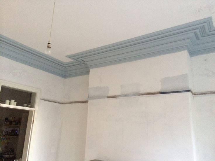 an empty room with white walls and blue trim on the ceiling is being painted by someone