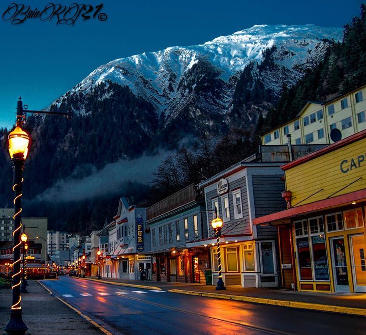 a street light sitting on the side of a road in front of snow covered mountains