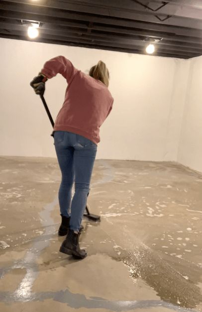 a woman is cleaning the floor in an empty room with no one around her and holding a mop