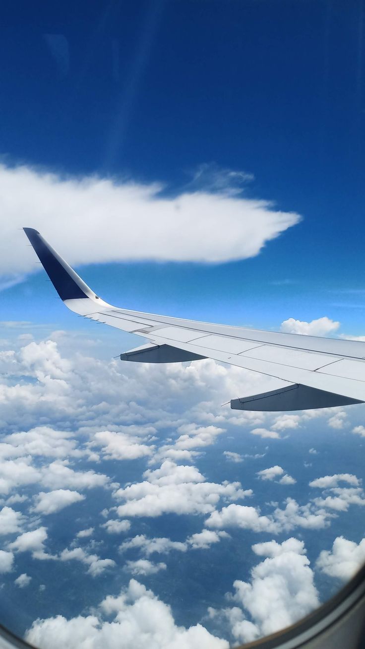 the wing of an airplane flying over clouds