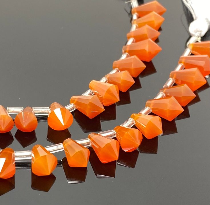 an orange necklace and earring set on a black surface