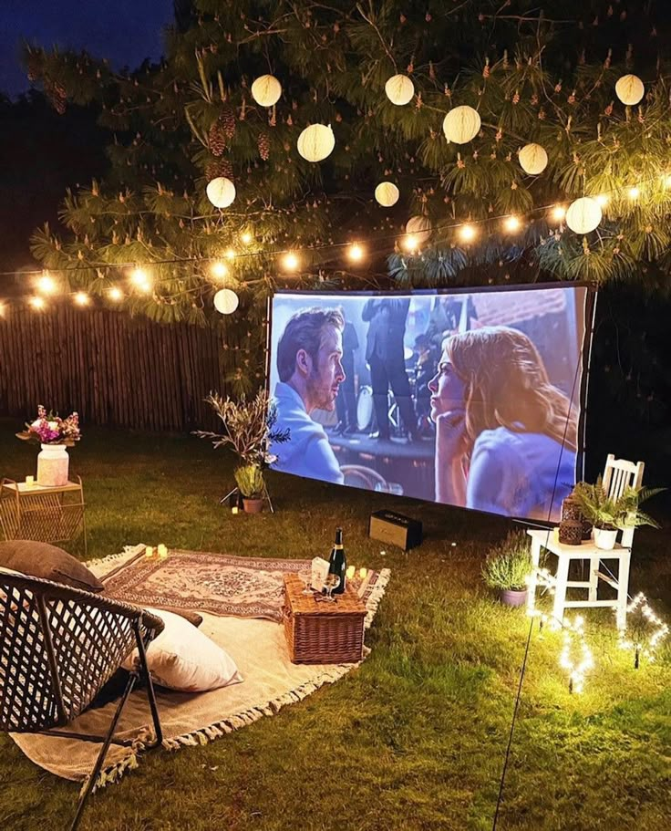 an outdoor movie is set up in the backyard with string lights strung across the lawn