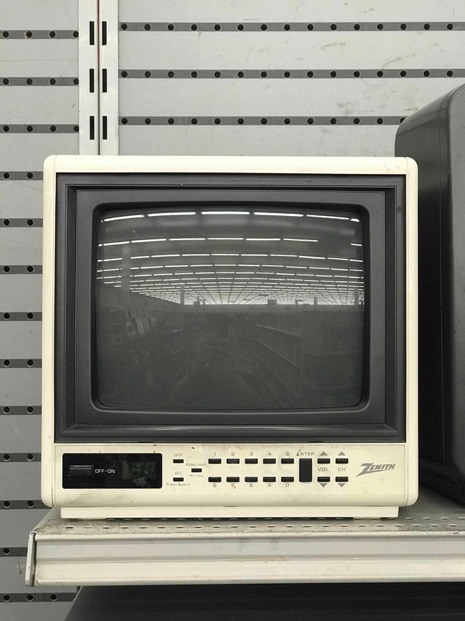 an old tv sitting on top of a shelf in front of a wall with wires