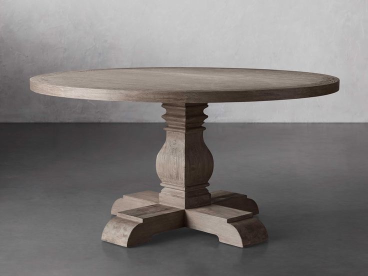 a round wooden table with two pedestals at the base and an oval wood table top