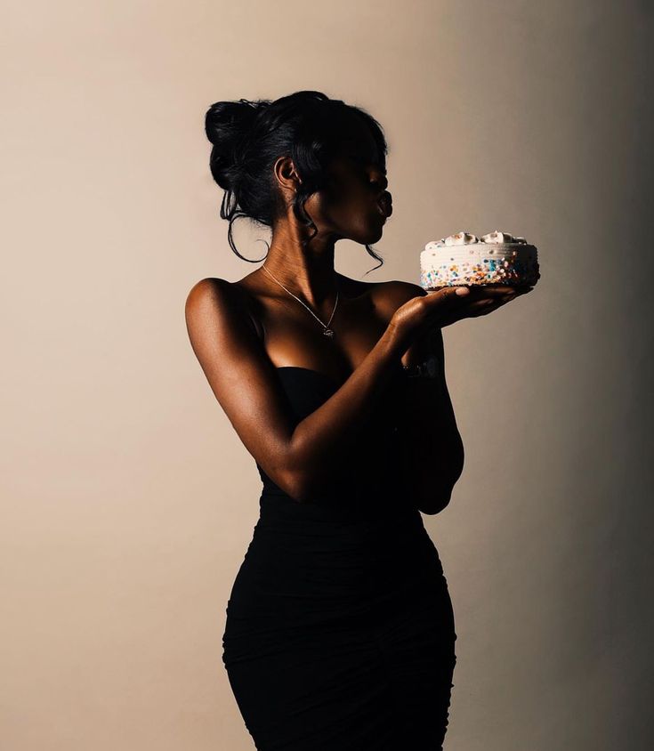 a woman in a black dress holding a cake