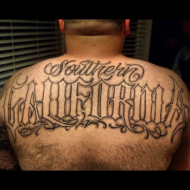 the back of a man's upper half - sleeved tattoo with words written in cursive font