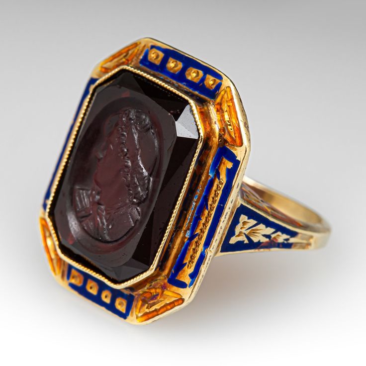 This unique and special circa 1900 Victorian intaglio ring features engraved details along the top and side faces with blue and orange enamel. The ring is accented with one (1) bezel set cut-cornered rectangular shaped intaglio cut garnet. The ring measures 20.7mm at the top, rises 6.5mm above the finger, tapering to 1.6mm wide and 1.0mm thick at the base of the shank. It is a size 4.75 and we are not offering resizing due to the enamel on the ring. It shows average wear for its age. Art Deco Enamel Rings For Formal Occasions, Art Deco Yellow Gold Enamel Ring For Formal Occasions, Art Deco Formal Yellow Gold Enamel Ring, Formal Yellow Gold Art Deco Enamel Ring, Formal Art Deco Yellow Gold Enamel Ring, Antique Enamel Ring Collectible, Victorian Enamel Ring For Formal Occasions, Antique Engraved Enamel Ring For Formal Occasions, Elegant Formal Enamel Signet Ring