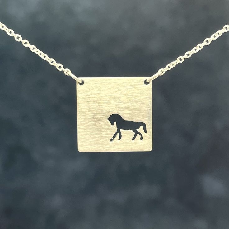 a gold necklace with a horse on it