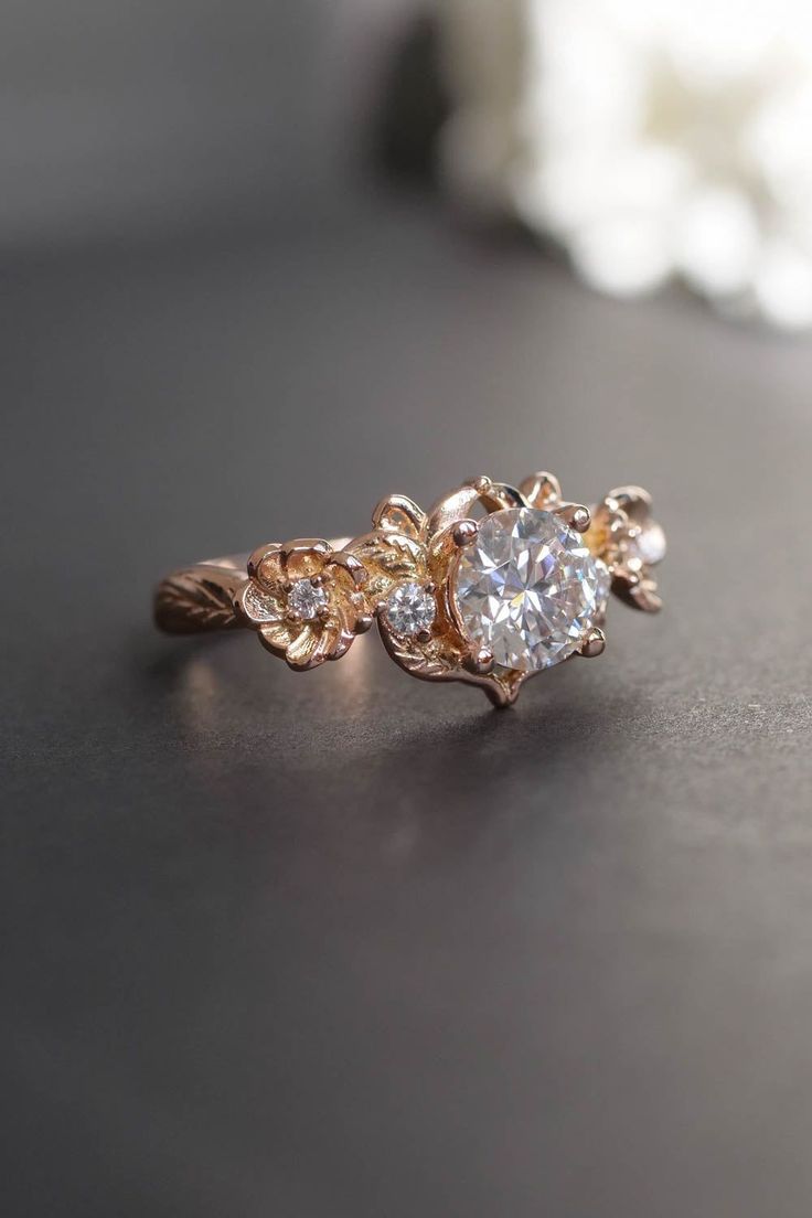 a close up view of a ring with flowers on the side and a diamond in the middle