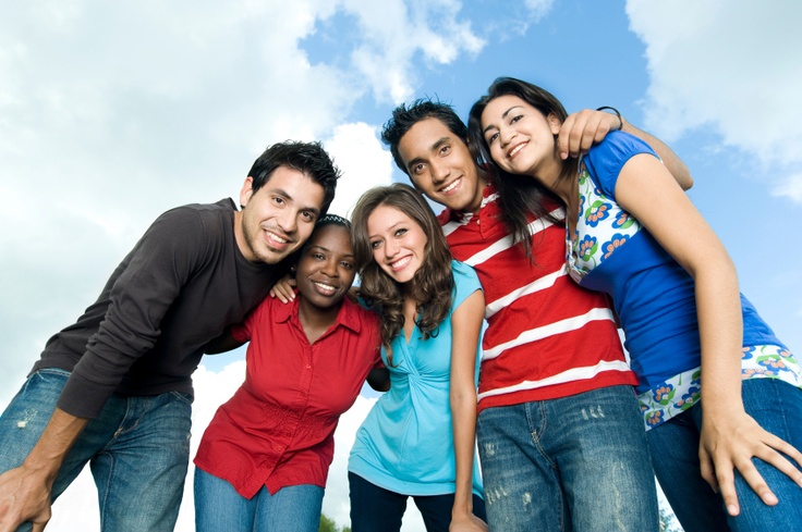 a group of young people standing next to each other in front of a blue sky