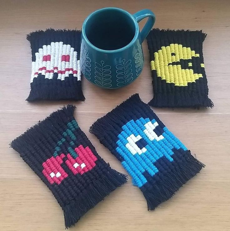 four pieces of bead art sitting on top of a wooden table next to a coffee mug