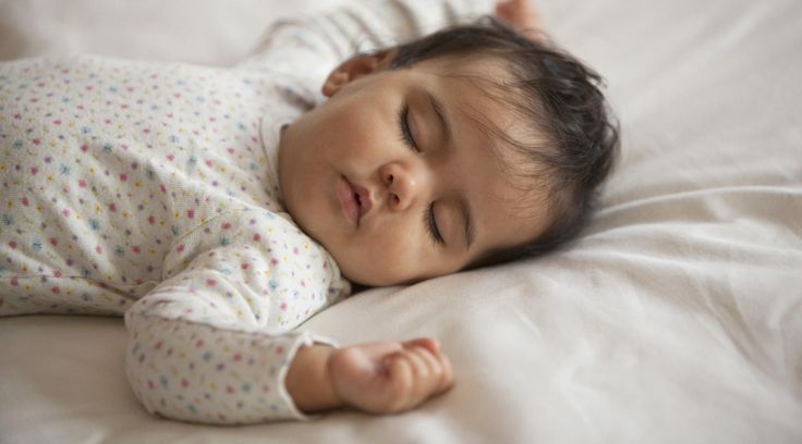 a baby is sleeping on a white sheet