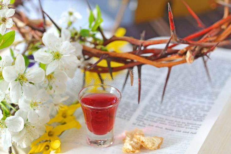 a glass of wine next to a crown of thorns and flowers on an open bible