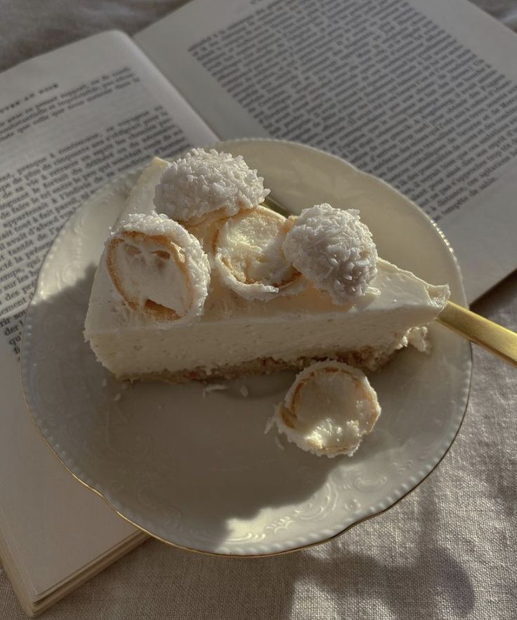 a slice of cheesecake on a plate next to an open book