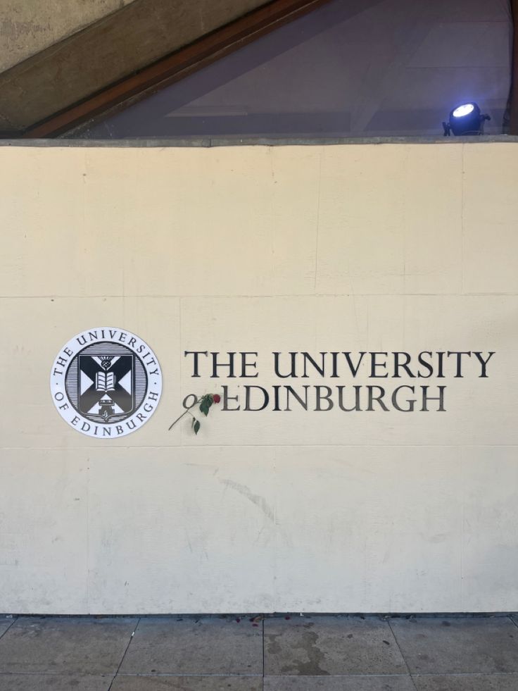 the university of edinburgh sign is shown in front of a building with a clock on it