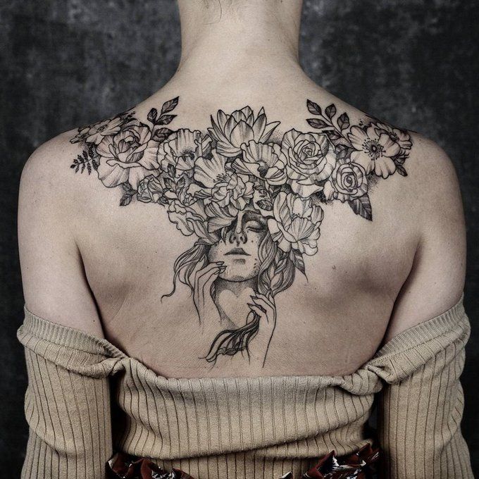 the back of a woman's shoulder with flowers on her neck and chest tattoo