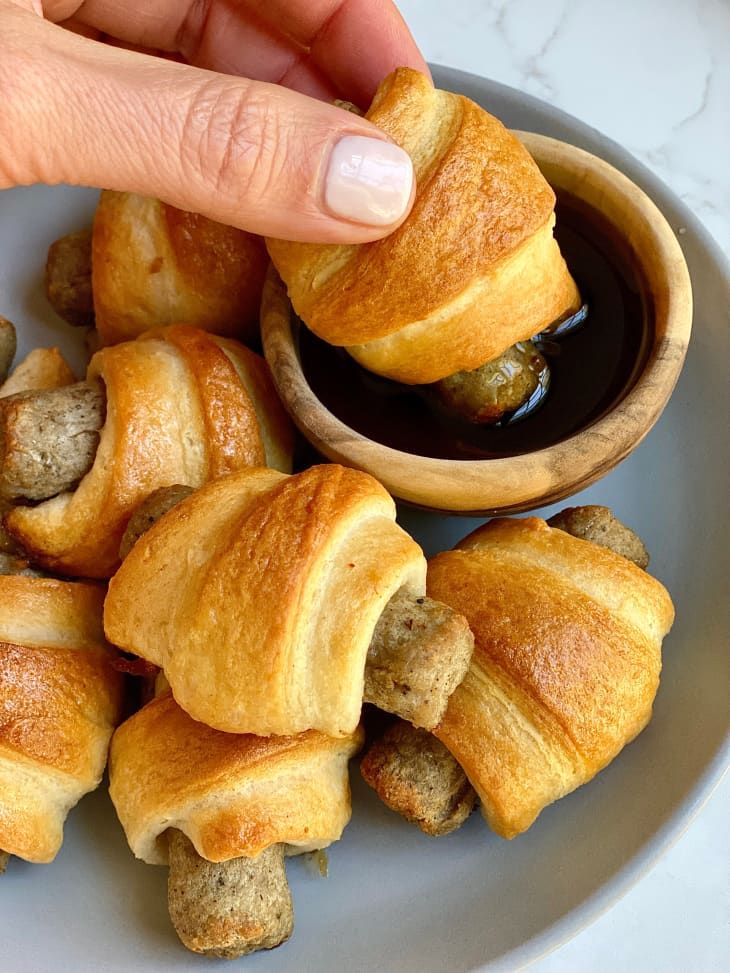 a person is picking up some food from a bowl on a plate with other pastries