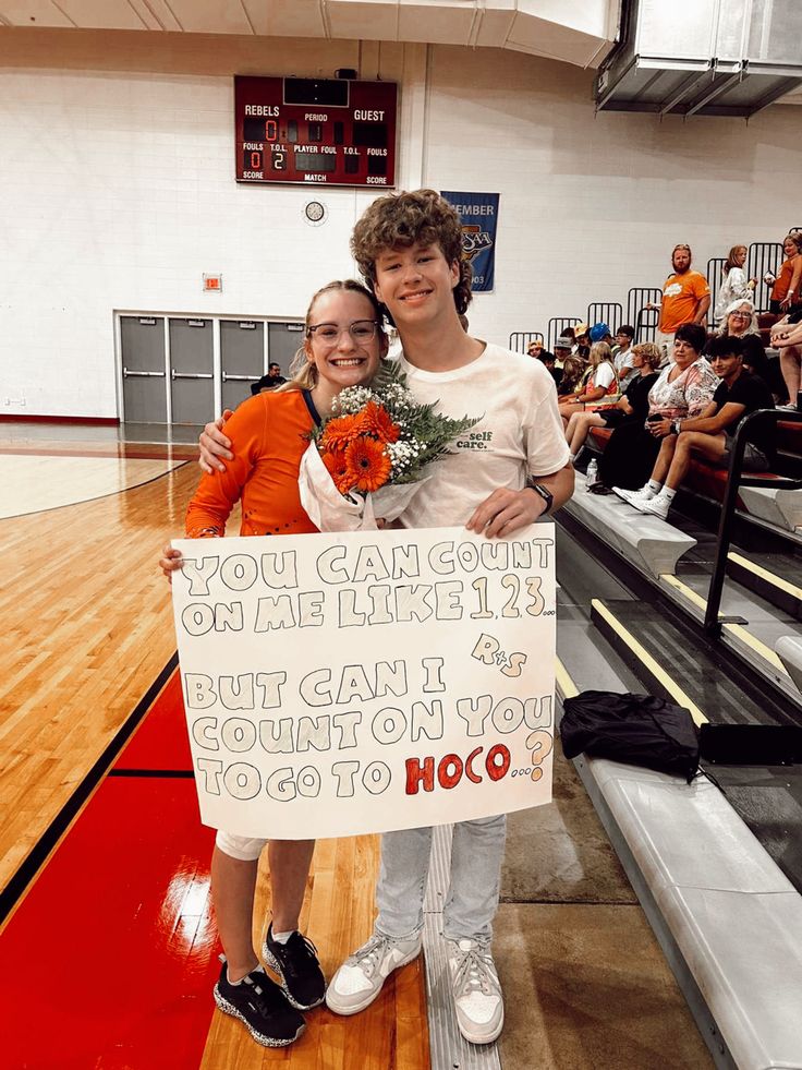 a young man and woman standing next to each other holding a sign