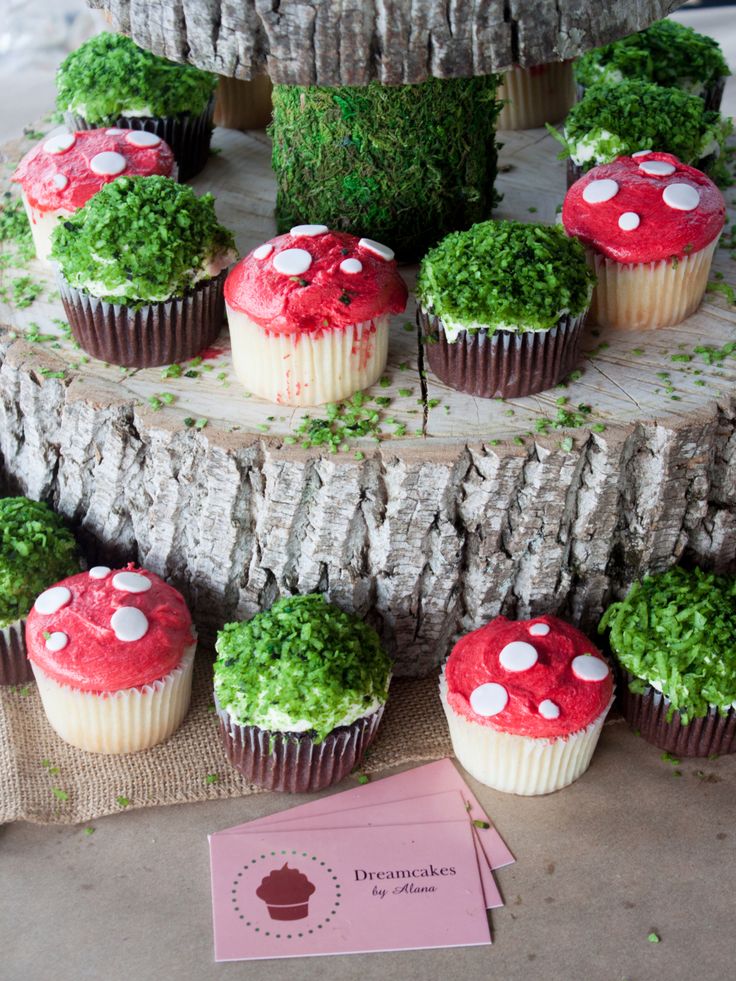 cupcakes with red and white frosting are arranged on a tree stump stand