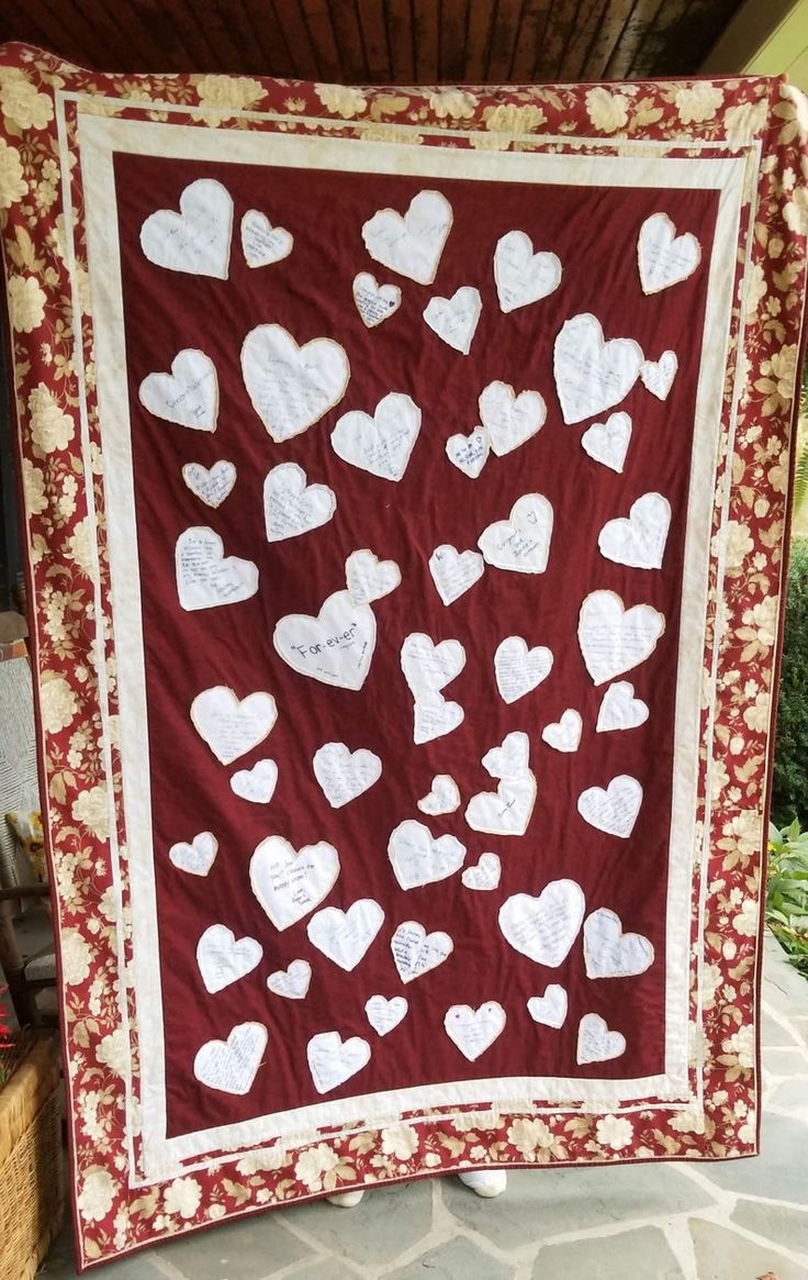 a red and white heart quilt hanging on a brick wall in front of a building