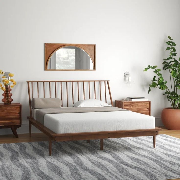 a bed sitting on top of a wooden floor next to a mirror and plant in a room