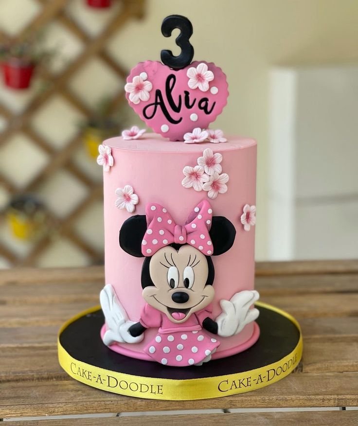 a pink and black cake with minnie mouse on top