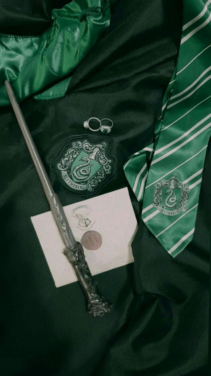 a harry potter tie, badge and keychain on a green satin bed spread