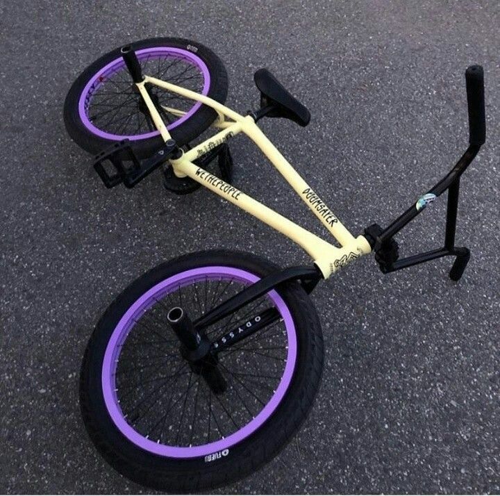 an upside down bike with purple rims on the pavement